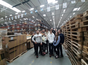 Klasa 4btl na hali firmy Decathlon, w tle europlaety i duże kartony z towarem.
