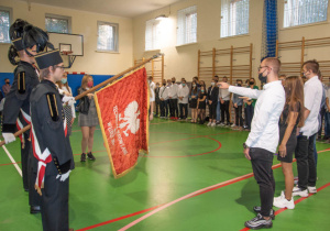 Uczniowie ślubują z ręą wyciągniętą w kierunku sztandaru