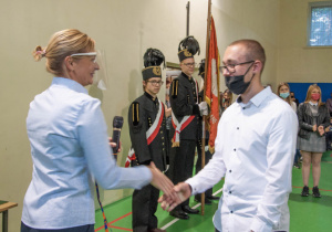 Dyrektorka wręcza legitymację uczniowi podczas ślubowania