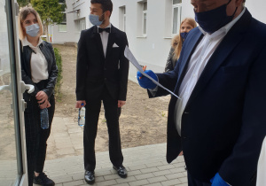 Grupa uczniow w dystansie spolecznym oczekuje na wejscie na egzamin