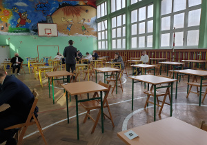 Uczniowie w sali gimnastycznej oczekuja na rozpoczecie egzaminu