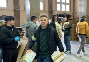 Uczniowie przenoszą paczki z darami uzbieranymi przez wolontariuszy